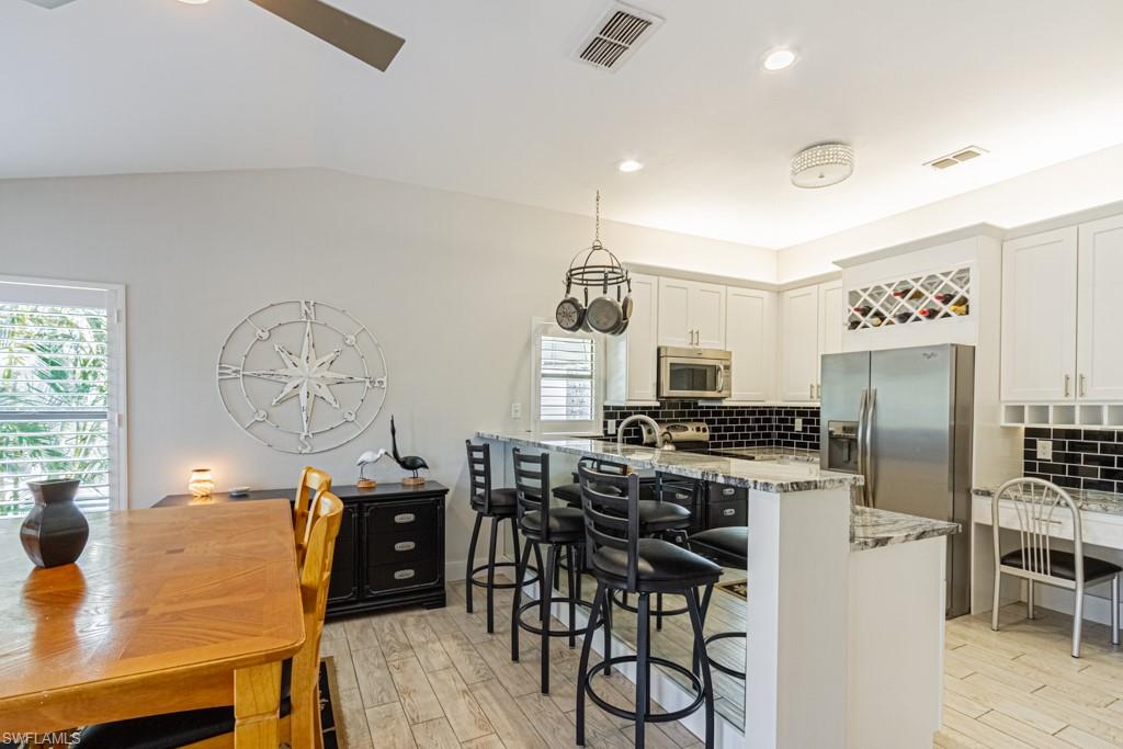 410 Panay Avenue Naples, FL 34113 - Photo 11 of 34 a kitchen with stainless steel appliances a stove a refrigerator a dining table and chairs