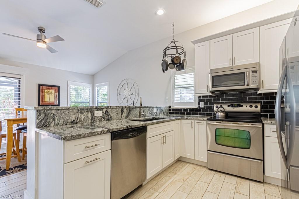 410 Panay Avenue Naples, FL 34113 - Photo 14 of 34 a kitchen with stainless steel appliances granite countertop a sink and stove top oven with white cabinets