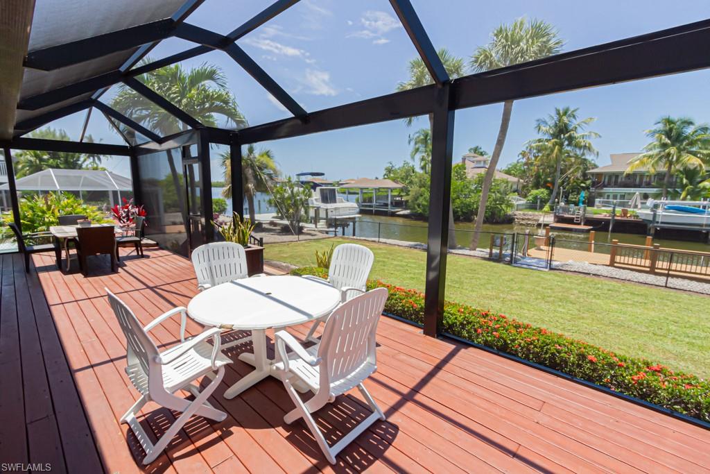 410 Panay Avenue Naples, FL 34113 - Photo 26 of 34 a view of a patio with lawn chairs floor to ceiling window and wooden floor