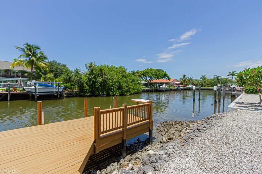 410 Panay Avenue Naples, FL 34113 - Photo 31 of 34 a view of a lake with wooden stairs and bridge and palm trees