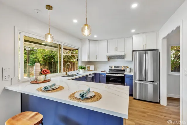 a kitchen with a refrigerator a stove a sink and a dining table with wooden floor