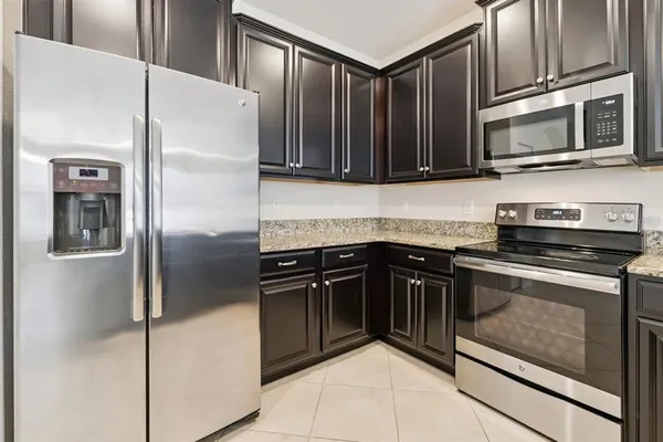 a kitchen with granite countertop a refrigerator stove and microwave