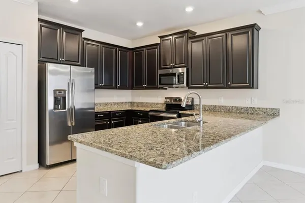 a kitchen with kitchen island granite countertop a sink a stove a refrigerator and a cabinets