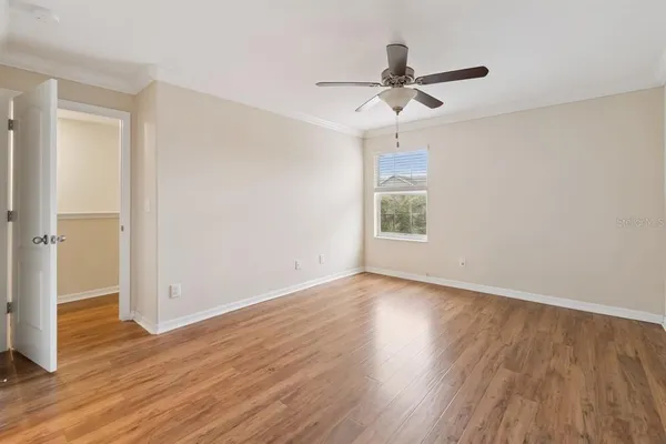 a view of empty room with wooden floor and ceiling fan