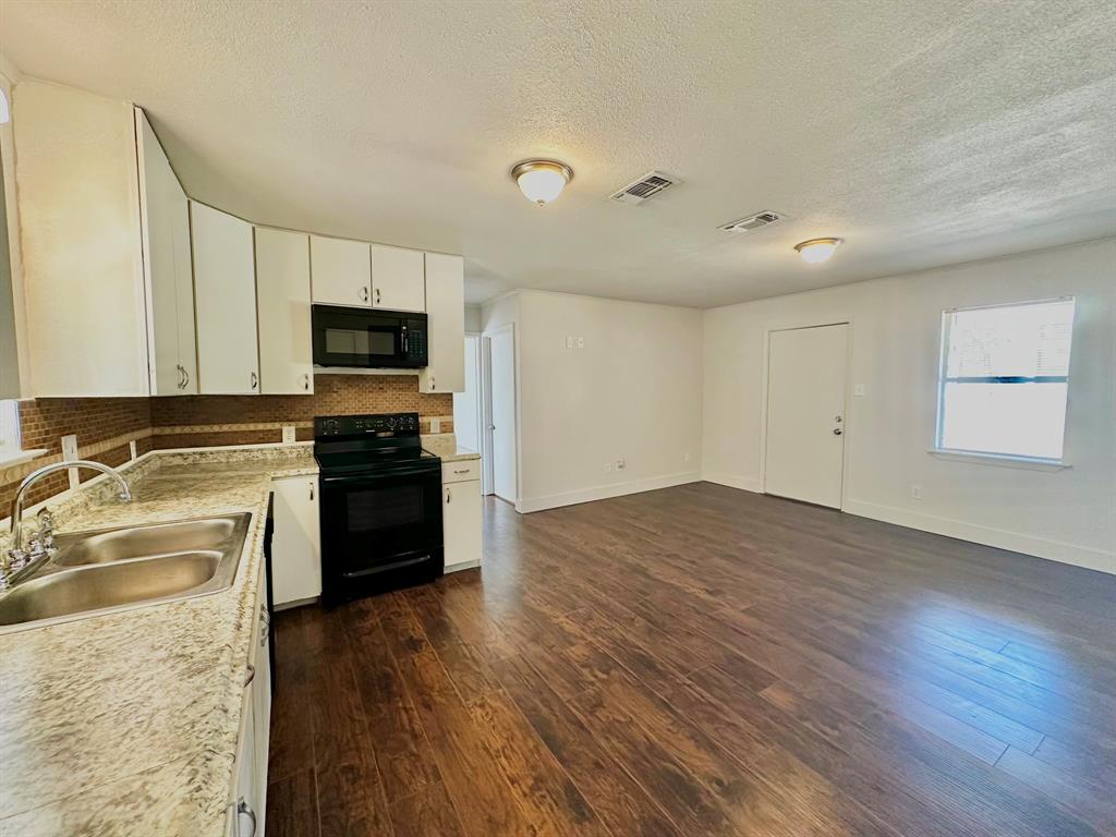 161 Elizabeth Street, Unit A Pottsboro, TX 75076 - Photo 3 of 20 a kitchen with wooden floors and black appliances