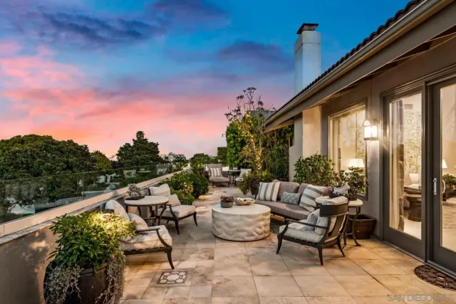 a roof deck with table and chairs and potted plants