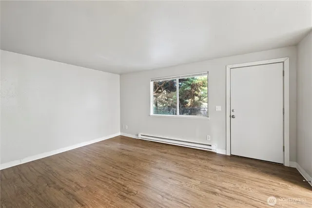 an empty room with wooden floor and windows