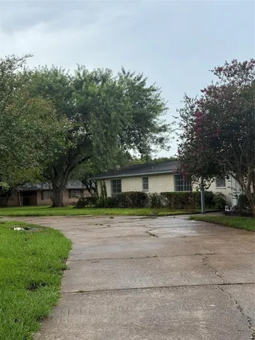 a view of a house with a yard and large trees