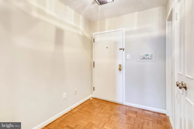 a view of an empty room with glass door and wooden floor