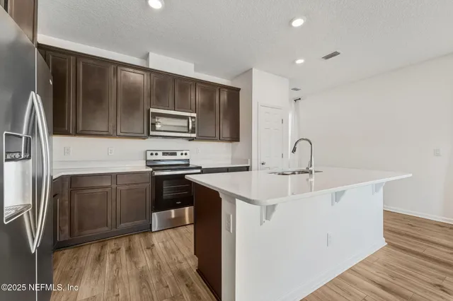 a kitchen with stainless steel appliances a sink cabinets and wooden floor
