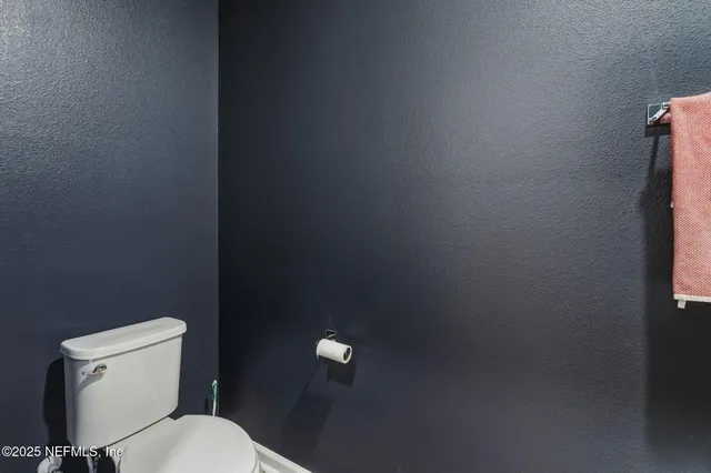 a white toilet sitting next to a white wall