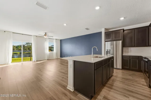 a kitchen with kitchen island granite countertop a sink cabinets and wooden floor