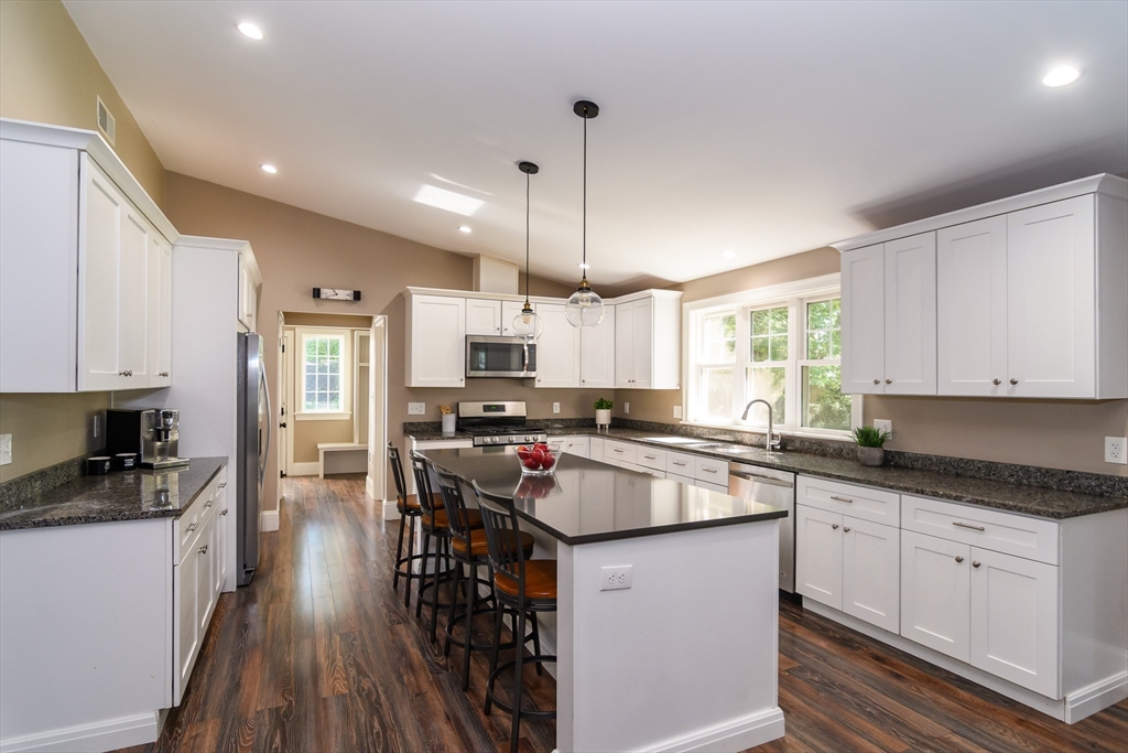 11 Leighton Street Natick, MA 01760 - Photo 7 of 27 a kitchen with stainless steel appliances granite countertop a stove top oven a sink a refrigerator white cabinets and wooden floor