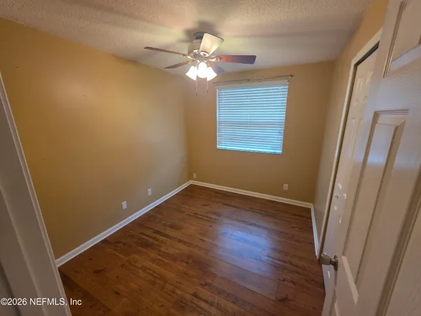 a view of an empty room with wooden floor and a window