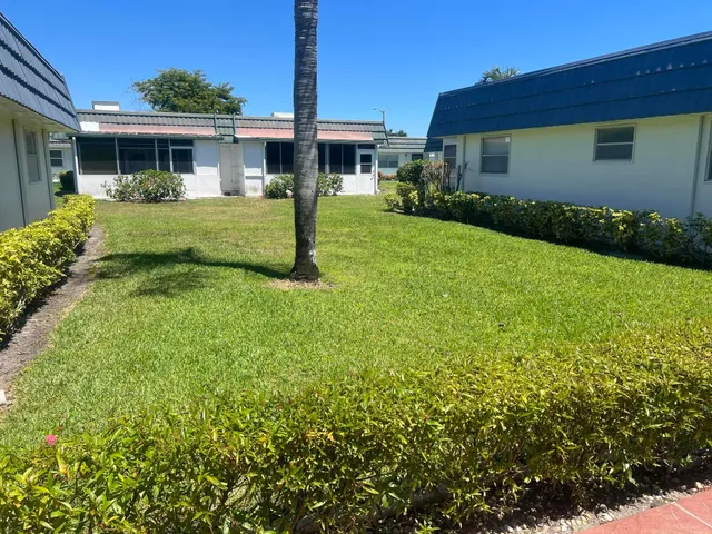 a view of a house with a big yard potted plants and a yard