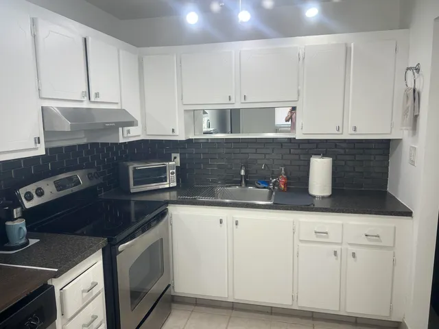 a kitchen with granite countertop white cabinets and stainless steel appliances