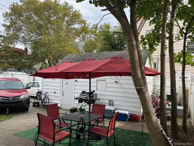 a view of a patio with table and chairs under an umbrella with large trees