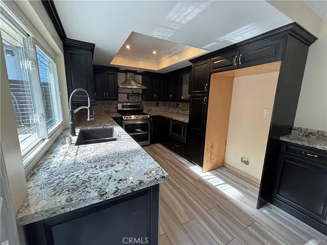 a kitchen with stainless steel appliances granite countertop sink stove refrigerator and cabinets