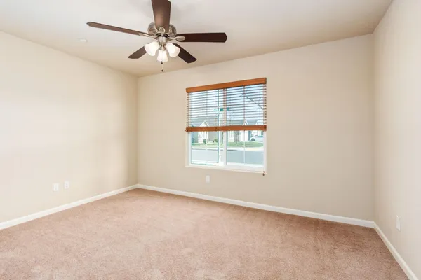an empty room with a window and a fan