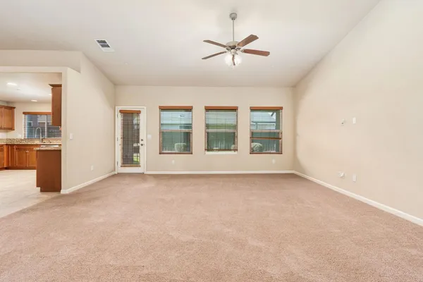 an empty room with chandelier fan and windows