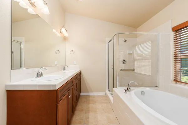 a spacious bathroom with a tub double sink and mirror