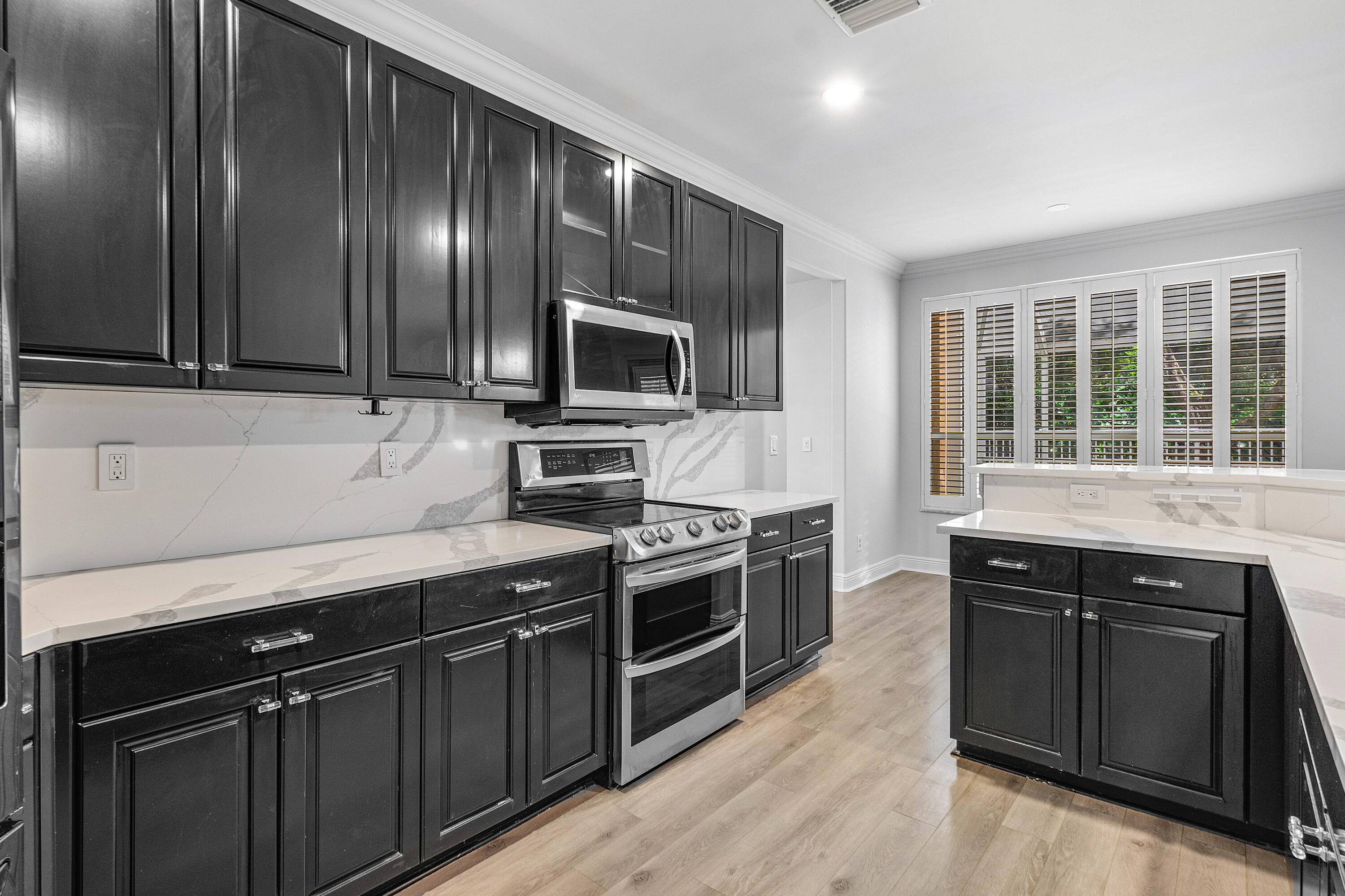 1655 East Classical Boulevard Delray Beach, FL 33445 - Photo 4 of 40 a kitchen with stainless steel appliances granite countertop wooden cabinets and a stove top oven