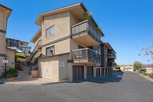 a view of a white building among the street with palm trees