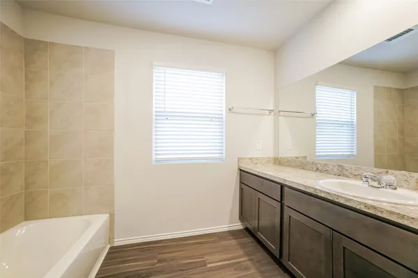 a bathroom with a granite countertop sink and a bathtub