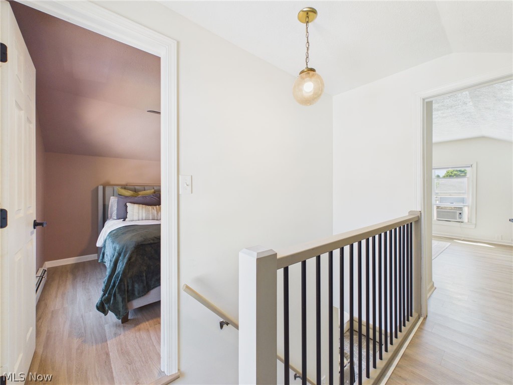 3490 County Line Road Madison, OH 44057 - Photo 31 of 42 Second-level landing featuring a contemporary gold-finish pendant light, wood-finish flooring, and a staircase with black metal balusters and a light wood-finish handrail