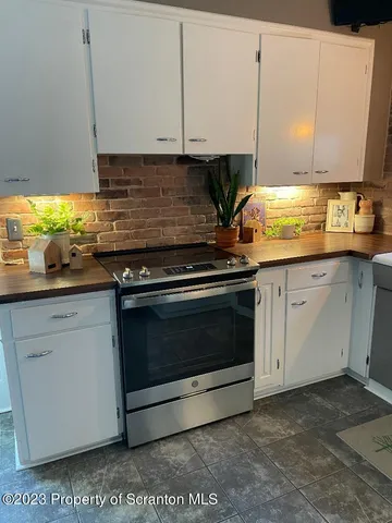 a kitchen with granite countertop a stove top oven a sink and white cabinets