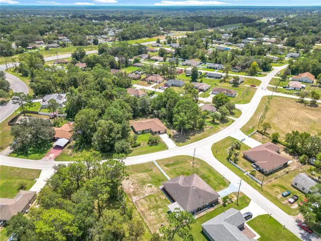 an aerial view of residential houses with outdoor space and trees