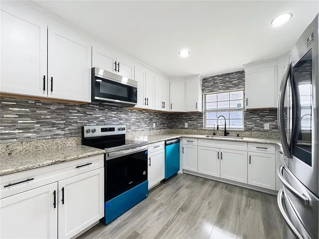 a kitchen with stainless steel appliances granite countertop a stove top oven a sink a microwave and cabinets