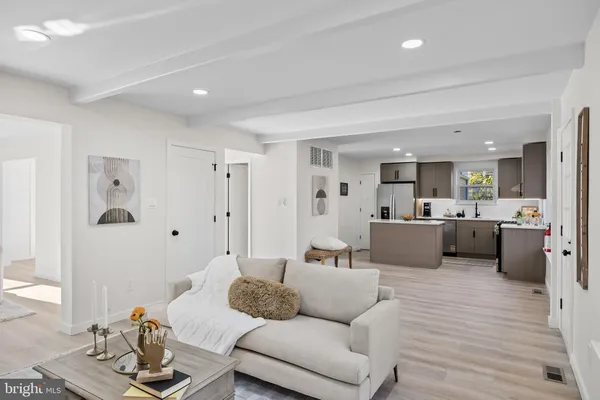 a living room with furniture kitchen view and a wooden floor