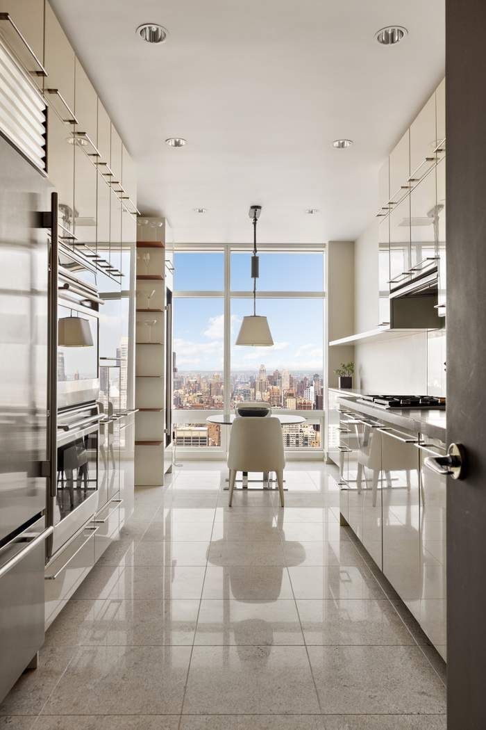 151 East 58th Street, Unit 35A Manhattan, NY 10022 - Photo 6 of 18 a kitchen with stainless steel appliances kitchen island granite countertop a refrigerator a stove and oven with wooden floor