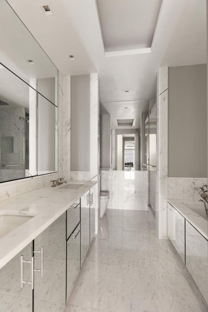 151 East 58th Street, Unit 35A Manhattan, NY 10022 - Photo 9 of 18 a large white bathroom with a granite countertop sink mirror and bathtub