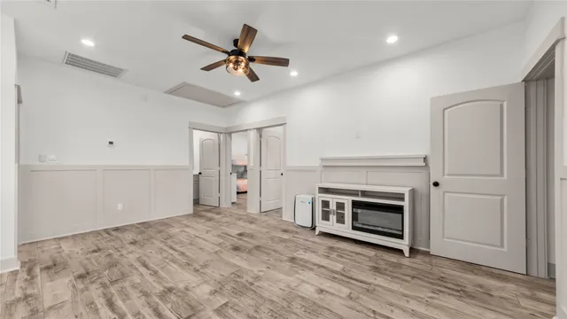 a view of a livingroom with a fireplace a ceiling fan and wooden floor