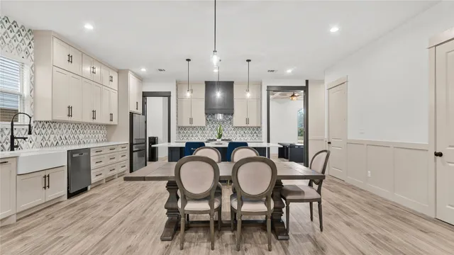 a large kitchen with cabinets wooden floor white stainless steel appliances and dining table