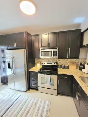 a kitchen with stainless steel appliances granite countertop a sink a stove a refrigerator and cabinets