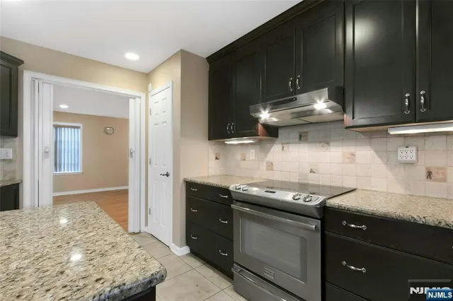 a kitchen with granite countertop stainless steel appliances a sink stove and cabinets