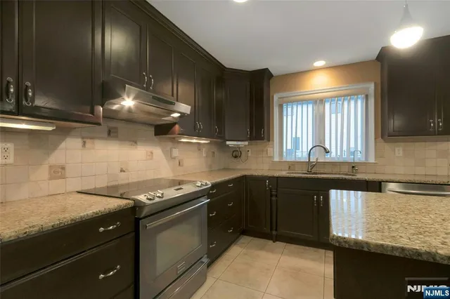 a kitchen with granite countertop stainless steel appliances a sink stove and cabinets