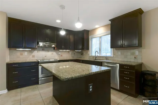 a kitchen with a sink and a stove top oven with wooden cabinets