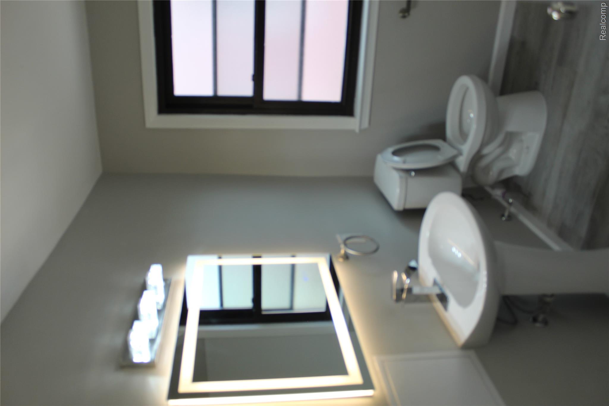 5543 Balfour Road Detroit, MI 48224 - Photo 12 of 54 Bathroom featuring a pedestal sink, backlit vanity mirror, and window with dark trim
