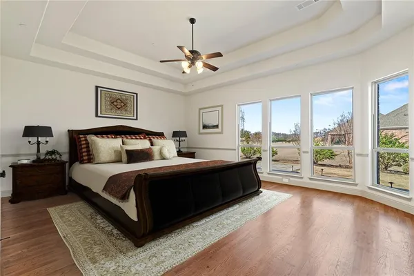 a spacious bedroom with a large bed and a chandelier fan