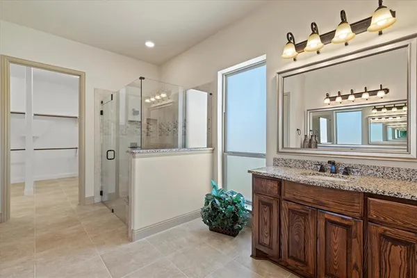 a bathroom with a sink vanity granite shower and a mirror