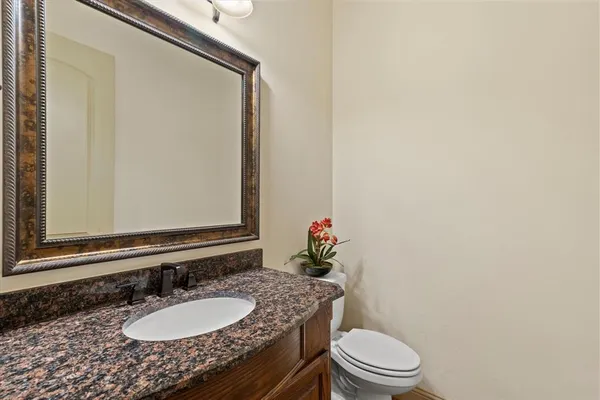 a bathroom with a granite countertop sink a toilet and a mirror