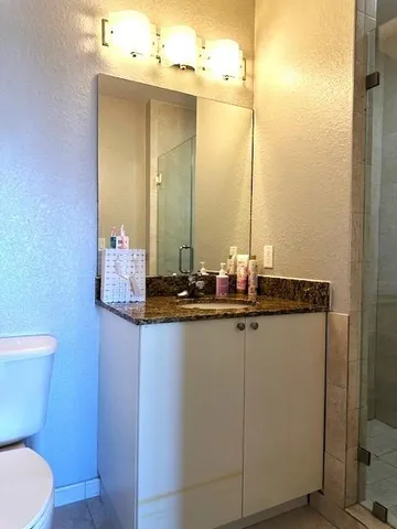 a bathroom with a granite countertop sink a toilet and a mirror