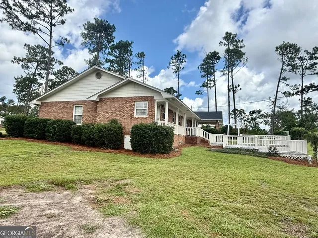 a view of a house with a yard and table and chairs under an umbrella