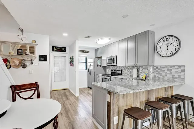 a kitchen with stainless steel appliances granite countertop a kitchen island a stove a table and chairs