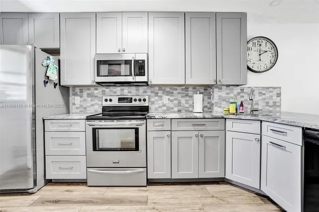 a kitchen with granite countertop white cabinets and stainless steel appliances