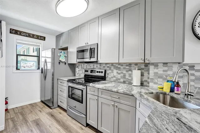 a kitchen with granite countertop a sink stainless steel appliances and cabinets